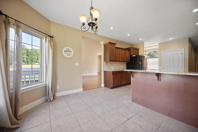 262 Silver Creek Dr, Somerset, KY 42503 - kitchen with black fridge, a kitchen bar, a chandelier, light tile patterned floors, and backsplash