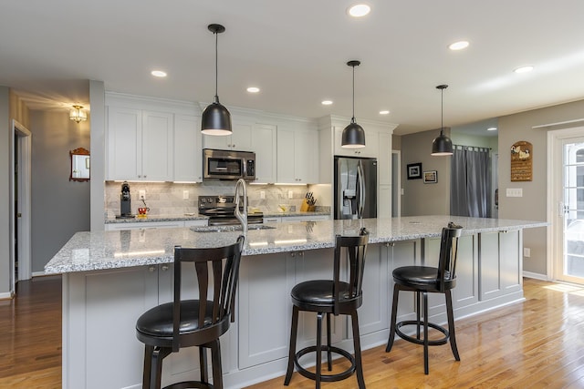 395 Redding Rd Unit 19, Lexington, KY 40517 - kitchen with appliances with stainless steel finishes, light wood-type flooring, backsplash, a sink, and a large island with sink