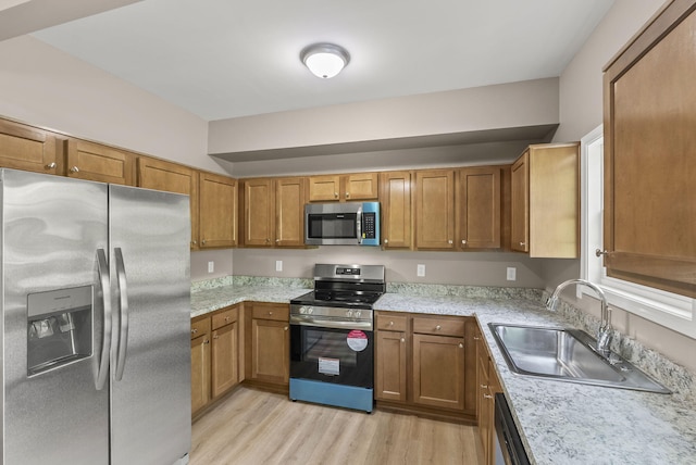 306 Young St, Georgetown, KY 40324 - kitchen with appliances with stainless steel finishes, a sink, brown cabinets, and light wood-style flooring