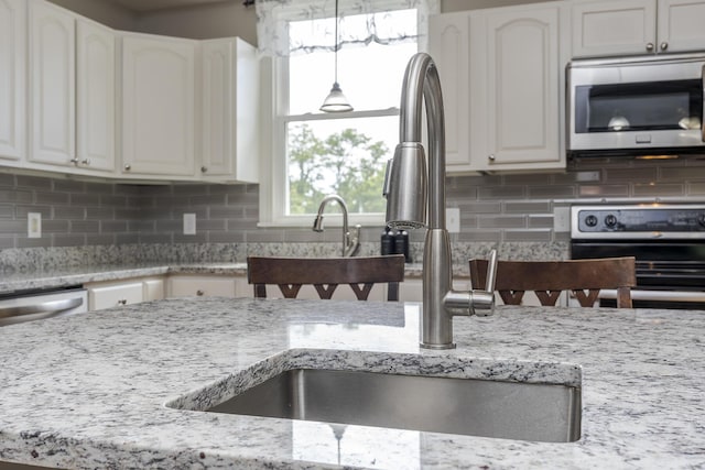 2018 E Ct, Richmond, KY 40475 - kitchen featuring appliances with stainless steel finishes, white cabinetry, light stone countertops, a sink, and backsplash