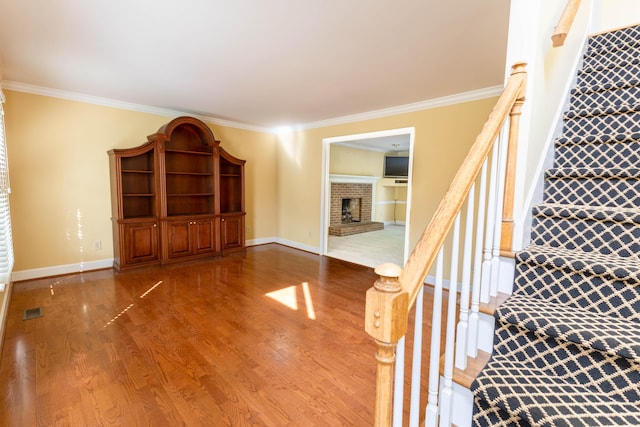 6011 Canonero Way, Versailles, KY 40383 - unfurnished living room with ornamental molding, wood finished floors, a brick fireplace, stairway, and baseboards