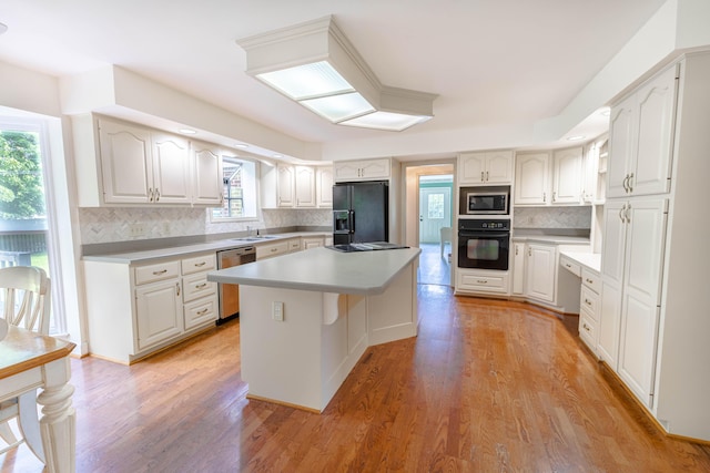 6011 Canonero Way, Versailles, KY 40383 - kitchen with black appliances, a sink, a kitchen island, backsplash, and light wood-type flooring
