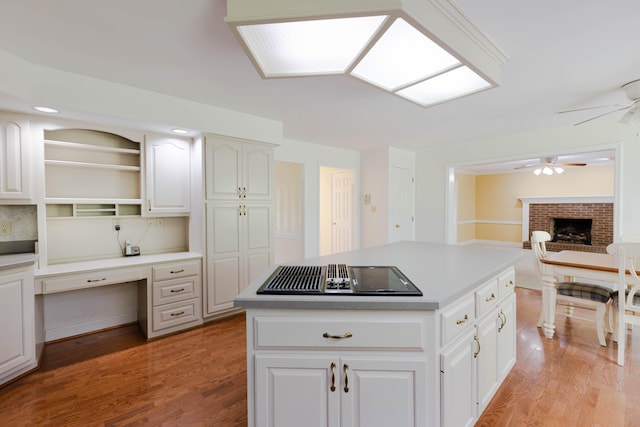 6011 Canonero Way, Versailles, KY 40383 - kitchen featuring stovetop with downdraft, ceiling fan, light wood-style floors, and a brick fireplace