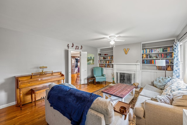 1023 Chickasaw Trl, Frankfort, KY 40601 - living area featuring wood finished floors, a ceiling fan, a fireplace, built in shelves, and baseboards