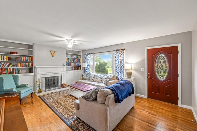 1023 Chickasaw Trl, Frankfort, KY 40601 - living area featuring wood finished floors, a ceiling fan, a fireplace, built in shelves, and baseboards
