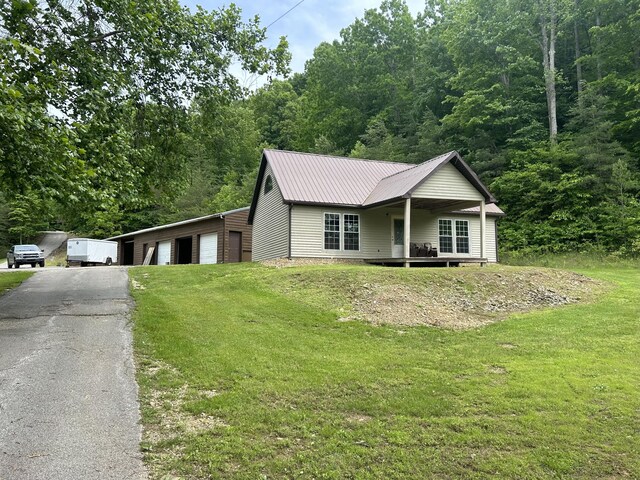 12430 E Ky-10, Quincy, KY 41166 - view of front of house featuring a front yard, a detached garage, metal roof, and a forest view