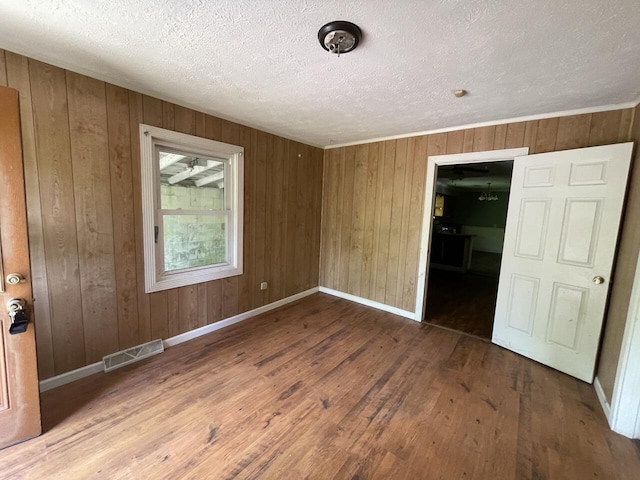 5069 Ky 11, Cannon, KY 40923 - spare room featuring wood-type flooring, wooden walls, baseboards, and a textured ceiling