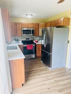 127 Circle St, London, KY 40744 - kitchen featuring stainless steel appliances, light countertops, brown cabinetry, light wood-style floors, and a sink