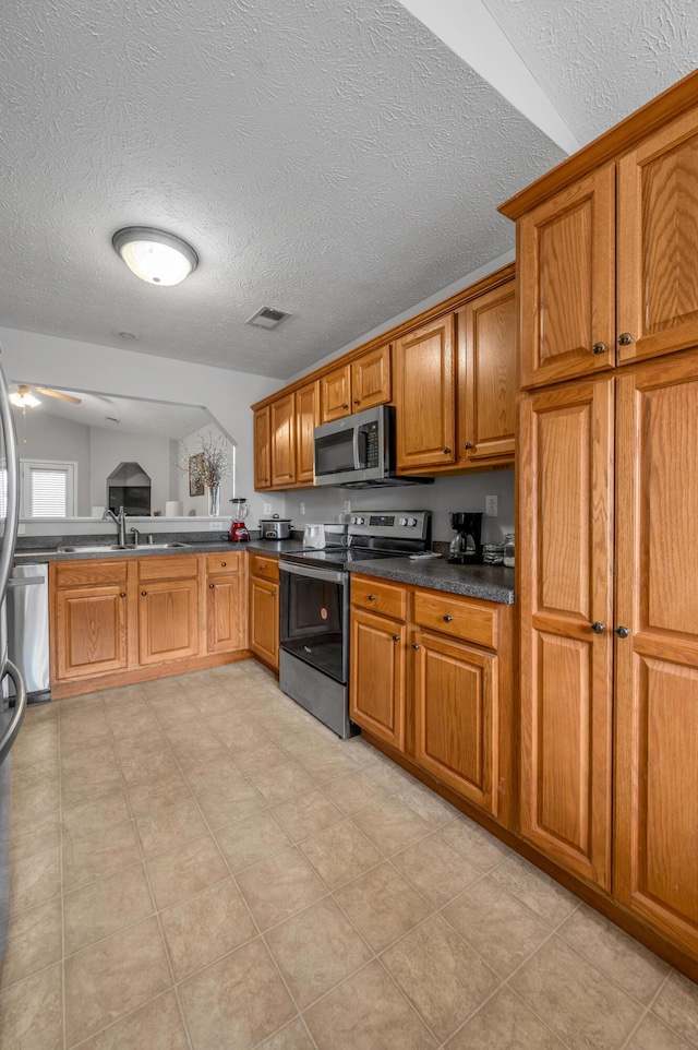 408 Joseph Bryan Way, Lexington, KY 40514 - kitchen featuring stainless steel appliances, brown cabinetry, a textured ceiling, dark countertops, and a sink
