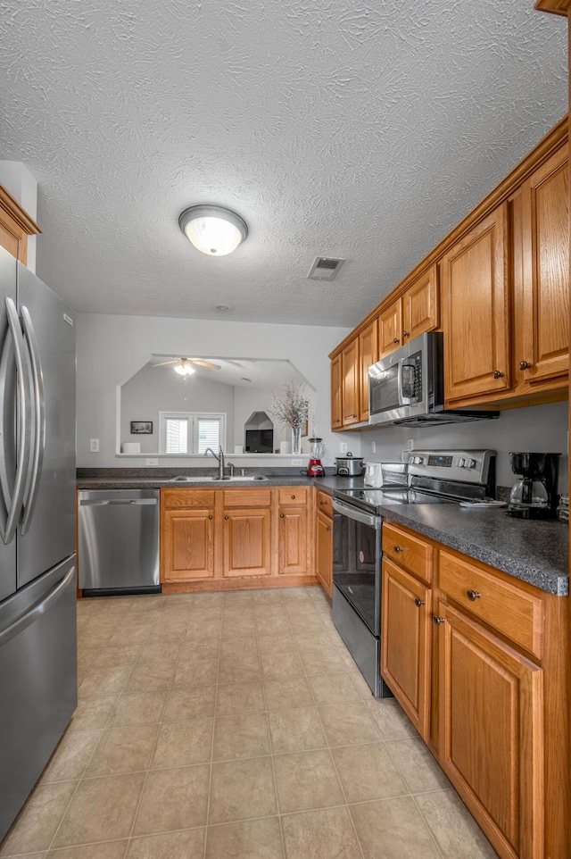 408 Joseph Bryan Way, Lexington, KY 40514 - kitchen featuring appliances with stainless steel finishes, a sink, brown cabinetry, dark countertops, and ceiling fan