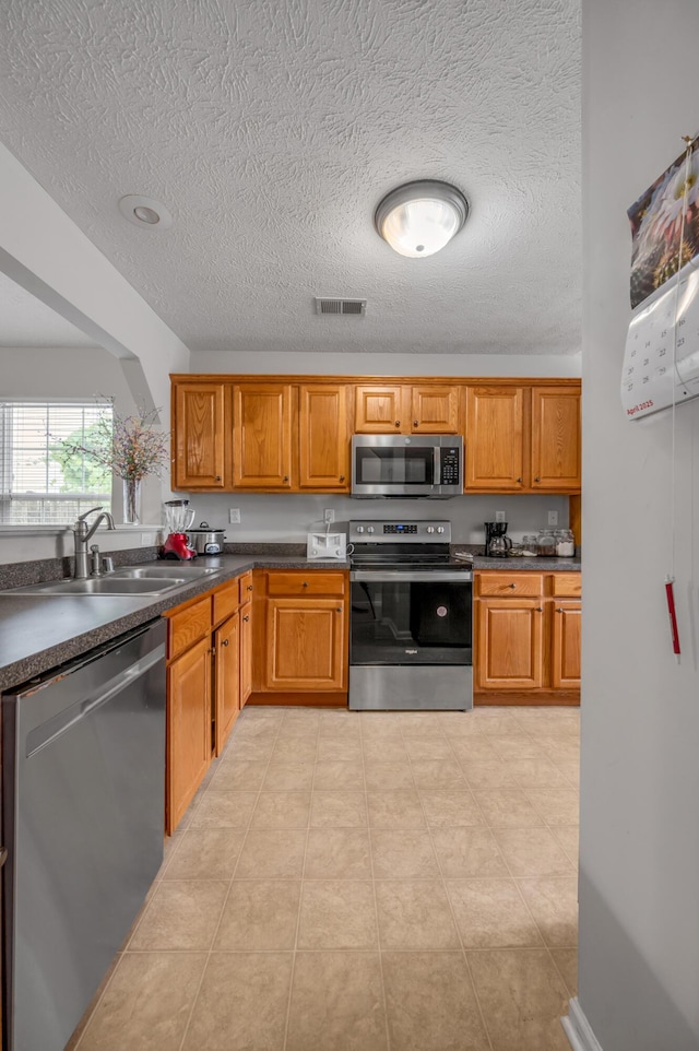 408 Joseph Bryan Way, Lexington, KY 40514 - kitchen with stainless steel appliances, a sink, dark countertops, a textured ceiling, and brown cabinets