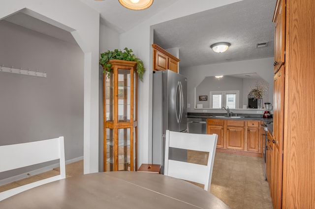 408 Joseph Bryan Way, Lexington, KY 40514 - kitchen with stainless steel appliances, a sink, brown cabinetry, a textured ceiling, and dark countertops