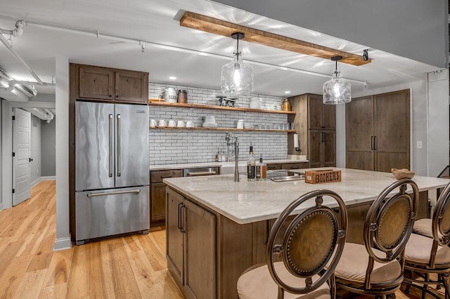 517 W Main St, Lexington, KY 40507 - kitchen featuring high end refrigerator, open shelves, a kitchen island, light wood-style floors, and light stone counters