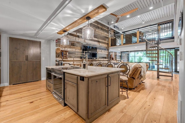 517 W Main St, Lexington, KY 40507 - kitchen featuring stainless steel range with electric cooktop, wooden walls, light wood-style flooring, beamed ceiling, and a kitchen island with sink