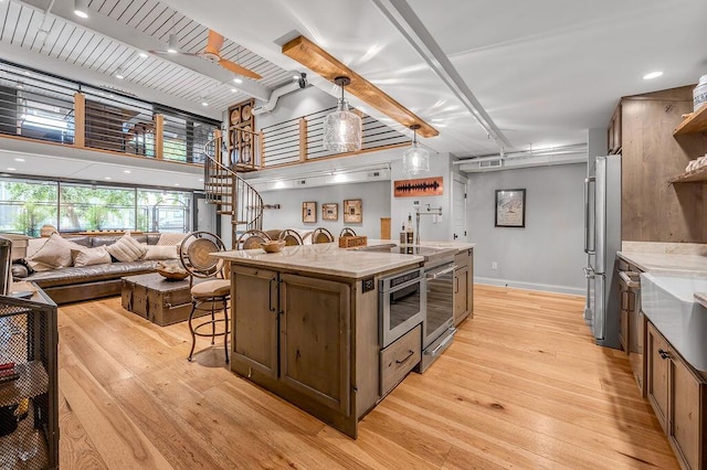 517 W Main St, Lexington, KY 40507 - kitchen with appliances with stainless steel finishes, a breakfast bar, light wood-type flooring, a kitchen island with sink, and a towering ceiling