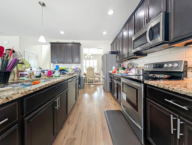 4663 Larkhill Ln, Lexington, KY 40509 - kitchen with stainless steel appliances, light stone countertops, backsplash, light wood-style floors, and hanging light fixtures