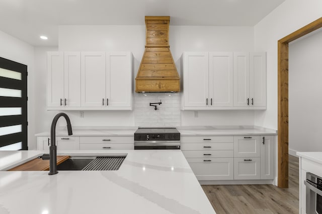 138 Hickory Grove Ln, Stanton, KY 40380 - kitchen with appliances with stainless steel finishes, custom range hood, white cabinetry, light wood-type flooring, and recessed lighting
