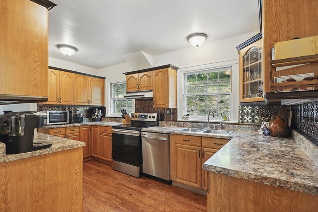 832 N 25th St, Middlesboro, KY 40965 - kitchen featuring a sink, appliances with stainless steel finishes, under cabinet range hood, decorative backsplash, and light wood-style floors