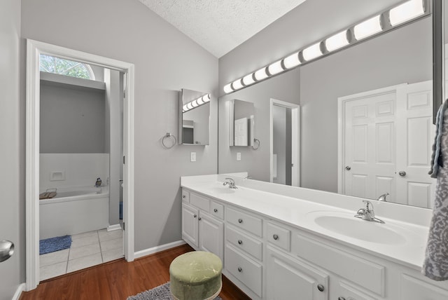 1217 Wyndham Hills Dr, Lexington, KY 40514 - full bathroom with lofted ceiling, a textured ceiling, double vanity, a bath, and wood finished floors