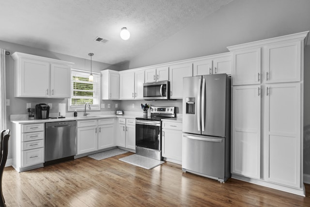 3648 Cottage Cir, Lexington, KY 40513 - kitchen featuring stainless steel appliances, lofted ceiling, white cabinetry, light countertops, and a textured ceiling