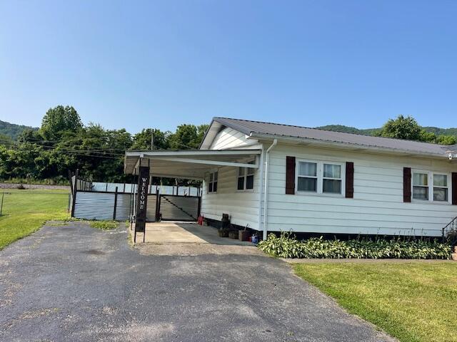 600 S 38th St, Middlesboro, KY 40965 - view of home's exterior with asphalt driveway, a lawn, an attached carport, and metal roof