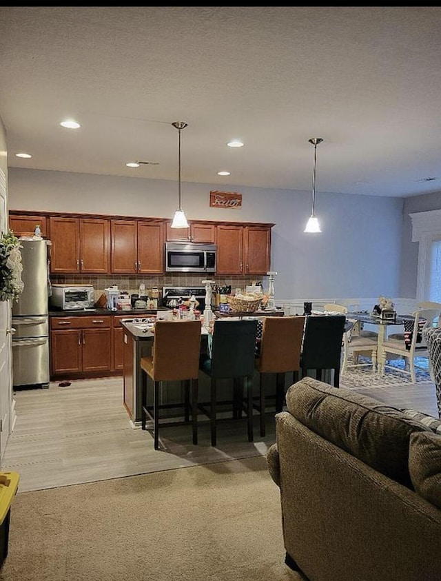 133 W Mcintosh Park, Georgetown, KY 40324 - kitchen with stainless steel appliances, a breakfast bar area, decorative backsplash, pendant lighting, and light carpet