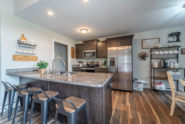 140 Central Park Ave, Berea, KY 40403 - kitchen with appliances with stainless steel finishes, a sink, dark brown cabinetry, light stone counters, and a breakfast bar area