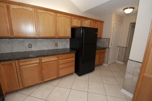 102 Academy Dr, Wilmore, KY 40390 - kitchen with freestanding refrigerator, tasteful backsplash, lofted ceiling, dark stone counters, and light tile patterned flooring