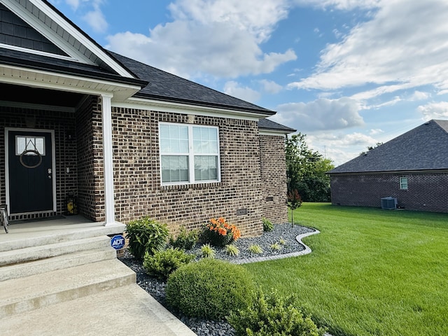 627 Fourwinds Dr, Richmond, KY 40475 - view of exterior entry with brick siding, a yard, roof with shingles, and cooling unit