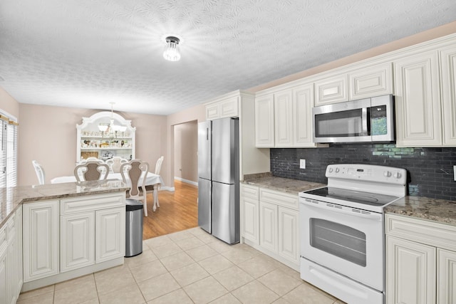 15 April Ln, Corbin, KY 40701 - kitchen featuring appliances with stainless steel finishes, light tile patterned flooring, a chandelier, tasteful backsplash, and a textured ceiling