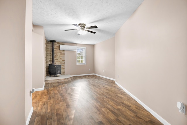 15 April Ln, Corbin, KY 40701 - unfurnished living room with a wood stove, a wall mounted AC, ceiling fan, wood finished floors, and a textured ceiling