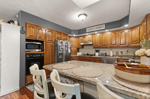 2003 Cresent Cir, Corbin, KY 40701 - kitchen featuring appliances with stainless steel finishes, a sink, under cabinet range hood, backsplash, and brown cabinetry