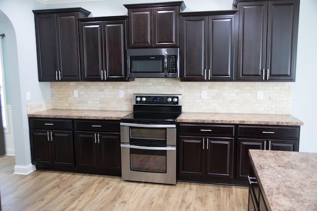 4745 Willman Way, Lexington, KY 40509 - kitchen featuring stainless steel appliances, arched walkways, light wood-style flooring, tasteful backsplash, and crown molding
