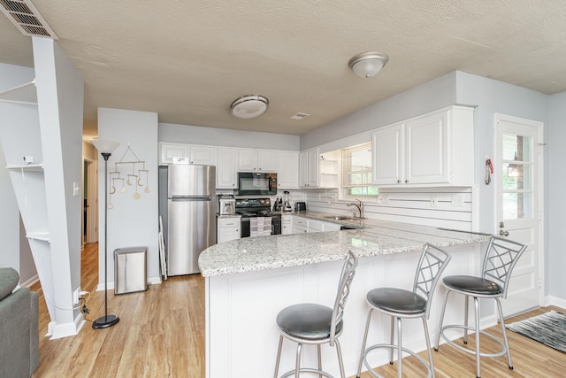 2812 Winter Park Dr, Lexington, KY 40517 - kitchen with black appliances, a peninsula, light stone countertops, white cabinets, and a textured ceiling