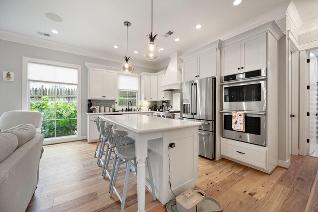 4291 Captains Ct, Lexington, KY 40513 - kitchen featuring appliances with stainless steel finishes, premium range hood, crown molding, a center island, and light countertops
