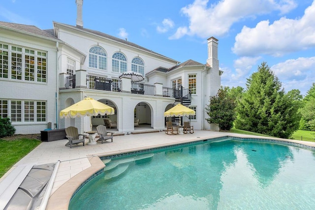 1617 Harmony Hall Ln, Lexington, KY 40502 - back of house with a balcony, a patio area, an outdoor pool, and a chimney