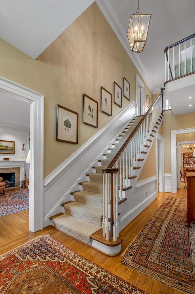100 Idle Hour Dr Unit 8, Lexington, KY 40502 - staircase featuring crown molding, wood finished floors, a chandelier, a fireplace, and a decorative wall