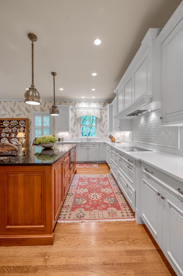 100 Idle Hour Dr Unit 8, Lexington, KY 40502 - kitchen with a sink, black electric cooktop, backsplash, white cabinetry, and pendant lighting