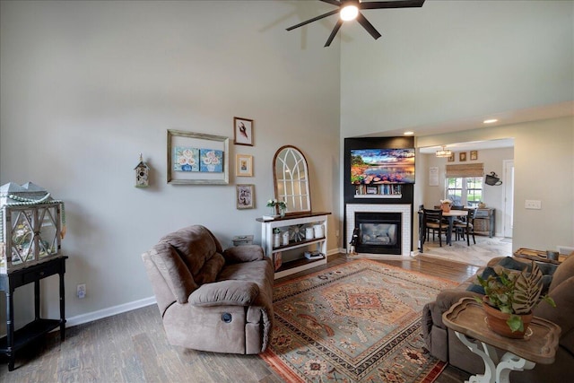 1202 Equestrian Way, Frankfort, KY 40601 - living room with wood finished floors, a ceiling fan, baseboards, a high ceiling, and a fireplace with flush hearth