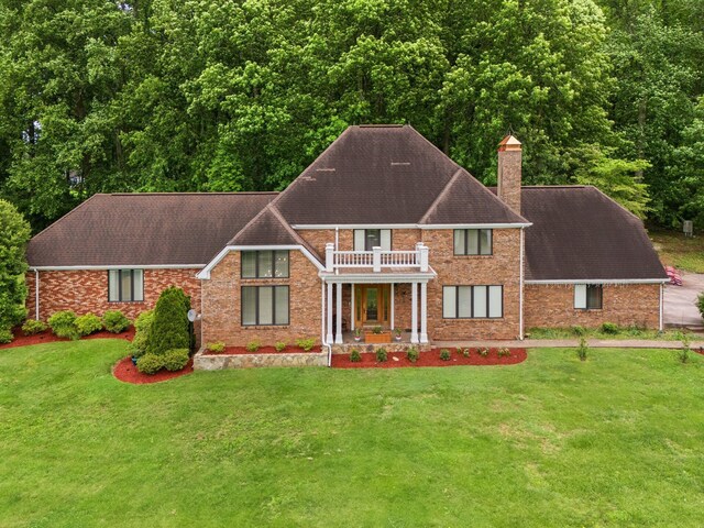 137 Indian Cave Subdivision, Monticello, KY 42633 - view of front of house featuring a balcony, a chimney, a front yard, roof with shingles, and brick siding