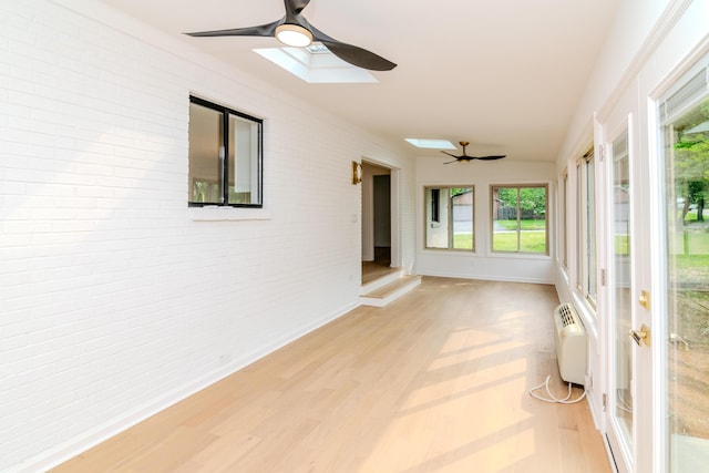 2933 Montavesta Rd, Lexington, KY 40502 - unfurnished sunroom with brick wall, a skylight, wood finished floors, a wall unit AC, and baseboards