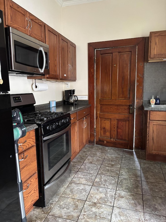 321 Clay Ave, Lexington, KY 40502 - kitchen with stainless steel appliances, ornamental molding, dark countertops, and brown cabinetry