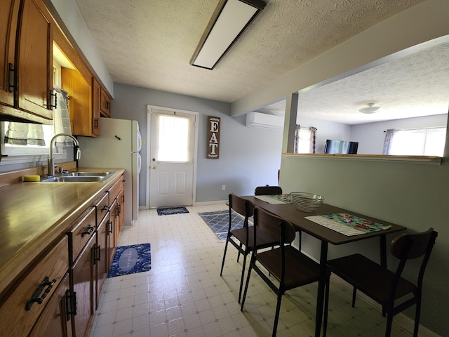 50 Ford Dr, Mount Vernon, KY 40456 - kitchen featuring brown cabinetry, a sink, a textured ceiling, light flooring, and an AC wall unit
