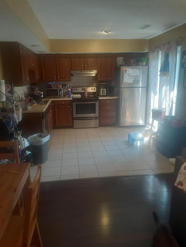414 Darby Creek Rd Unit B, Lexington, KY 40509 - kitchen featuring stainless steel appliances, under cabinet range hood, light countertops, light tile patterned floors, and brown cabinets