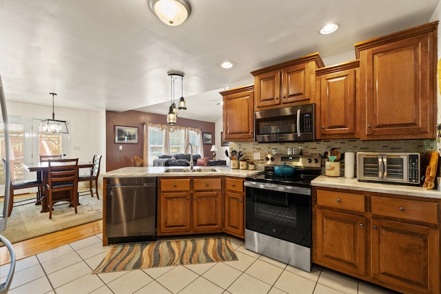 204 Keith Dr, Berea, KY 40403 - kitchen featuring stainless steel appliances, a sink, a peninsula, light countertops, and brown cabinetry