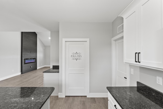 202 Max Cavnes Rd, Danville, KY 40422 - kitchen with light wood-style floors, a large fireplace, dark stone counters, white cabinetry, and open floor plan