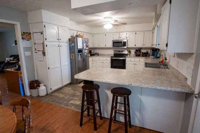 1987 White Rock Rd, Mount Vernon, KY 40456 - kitchen with appliances with stainless steel finishes, a peninsula, a sink, white cabinets, and dark wood-type flooring