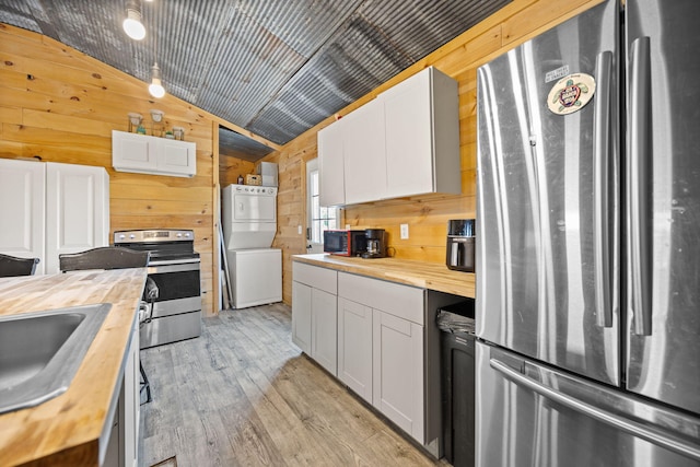 3402 Roundtop Rd, Strunk, KY 42649 - kitchen featuring wood counters, stainless steel appliances, stacked washer / drying machine, wood walls, and lofted ceiling