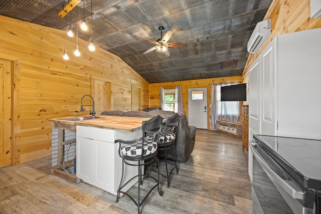 3402 Roundtop Rd, Strunk, KY 42649 - kitchen featuring butcher block countertops, an AC wall unit, a sink, lofted ceiling, and an island with sink