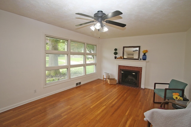 325 Dantzler Ct, Lexington, KY 40503 - living area featuring light wood finished floors, a brick fireplace, baseboards, a ceiling fan, and a textured ceiling